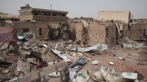 A man walks by a house hit in recent fighting in Khartoum, Sudan