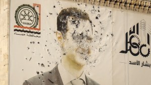 An image of Syrian President Bashar Assad, riddled with bullets, is seen on the facade of the provincial government office in the aftermath of the opposition's takeover