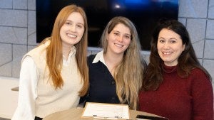 Three staff members pose while standing around a table