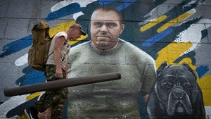 A fisherman passes by a mural in Kyiv depicting the head of Ukraine's Security Service Vasyl Malyuk 