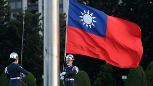 Two soldiers lower the Taiwan national flag at the Chiang Kai-shek Memorial Hall in Taipei, Taiwan on April 29, 2025.