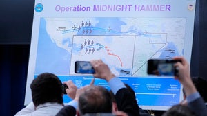 Reporters take photos of a graphic displaying information on Operation Midnight Hammer