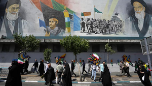 Iranian worshippers walk past a mural showing the late revolutionary founder Ayatollah Khomeini, right, Supreme Leader Ayatollah Ali Khamenei, left, and Basij paramilitary force in Tehran, Iran on April 19, 2024.