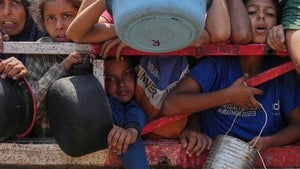 Palestinians push up against a fence waiting for food at a community kitchen in Gaza City on July 26, 2025.