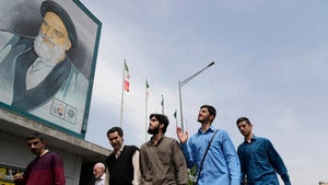 Iranians walk under a mural of the late Iranian revolutionary founder Ayatollah Khomeini