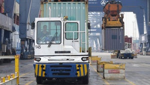 Cranes unload shipping containers from trucks at Jakarta International Container Terminal in Indonesia