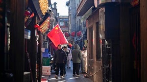 People walk past a Chinese flag in a Beijing commercial area on February 3, 2025. 