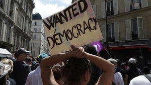 A protestor holds up a sign reading "WANTED DEMOCRACY" at a protest in France on July 31, 2021.