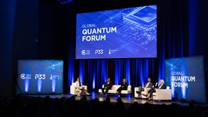 Five people sit in white chairs on a stage while having a discussion