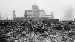 A man stands in a sea of rubble before the shell of a building that once was a movie theater in Hiroshima