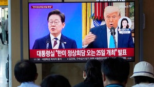 People watch a TV screen showing an image of South Korean President Lee Jae Myung and US President Donald Trump during a news program at the Seoul Railway Station