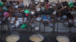 Palestinians struggle to get donated food at a community kitchen in Gaza City, northern Gaza Strip, Monday, July 14, 2025. 