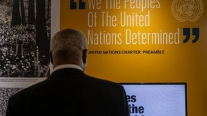 A man looks at a quote from the United Nations Charter: Preamble on a wall that reads: "We The Peoples Of The United Nations Determined."