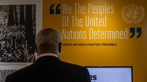 A man looks at a quote from the United Nations Charter: Preamble on a wall that reads: "We The Peoples Of The United Nations Determined."