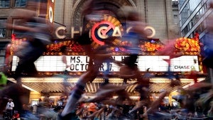Chicago Marathon runners run past the Chicago Theatre marquee.