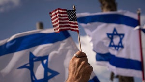a person holds an American flag in front of Israeli flags