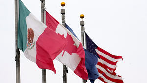 Flags of Mexico, Canada, and the United States flying from flagpoles.