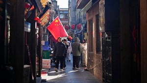 People walk past a Chinese flag in a commercial area in Beijing