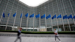 European Union flags flap in the wind as pedestrians walk by EU headquarters in Brussels