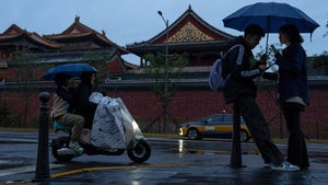 A couple chat as they share an umbrella during a rainy day in Beijing