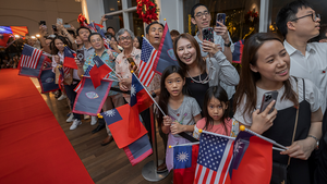 People in a crowd hold Taiwan and US flags as they welcome Taiwanese President Lai Ching-te to Guam on December 4, 2024.