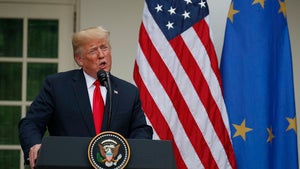 Donald Trump stands in front of US and EU flags