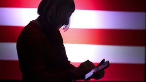 a person looks at their phone in front of an American flag backdrop