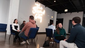 YP Members sit in groups in front of a sign reading The Second City
