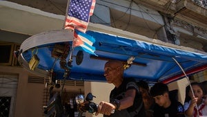 A driver steers his bicycle taxi decorated with US and Cuban flags in Havana, Cuba