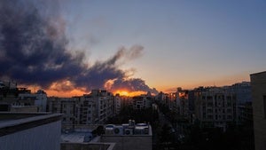 The sun sets behind a plume of smoke rising after a US–Israeli military strike in Tehran, Iran.