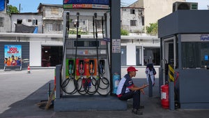 A worker gestures to indicate "no gas" at a gasoline station in the Philippines