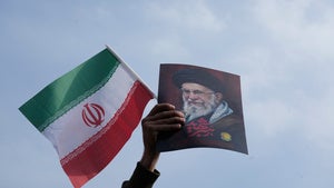 A man holds up an Iranian flag and a poster of the late Supreme Leader Ayatollah Ali Khamenei
