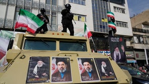 Policemen stand on top of their car with pictures of the late Iranian Supreme Leader Ayatollah Ali Khamenei and his son Ayatollah Mojtaba Khamenei