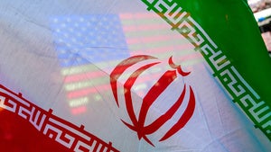 A US flag is seen through the flag of Iran