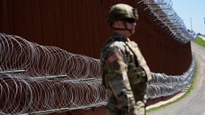 a guard stands in front of the US-Mexico border wall