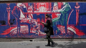 A woman walks past an anti-US mural painted on the wall of the former US embassy in Tehran