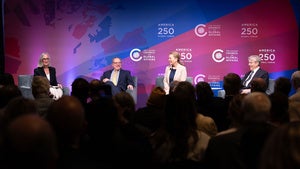 Four people sitting on a stage in front of an audience