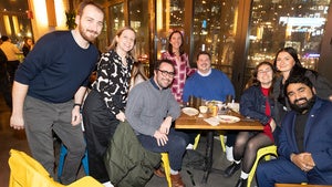 A group of people pose around a table