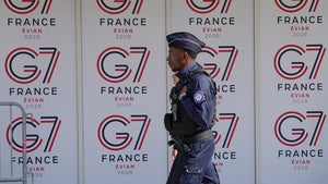A French police officer walks past G7 logos in Evian-les-Bains