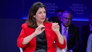 A woman speaks while sitting in a chair on-stage