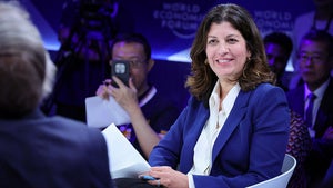 A woman smiling while speaking to someone on stage