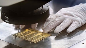 A factory working lining up a data chip under a machine.