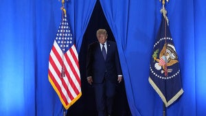 President Donald Trump walks through blue curtains