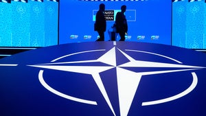 Two men walk past the NATO logo
