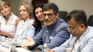 Samir Saran speaks to group of people around a table.