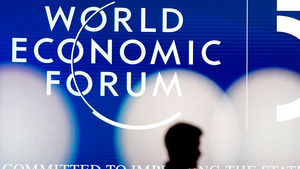 A person's silhouette in front of a sign for the World Economic Forum.