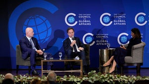 Three people sit in chairs while speaking into microphones
