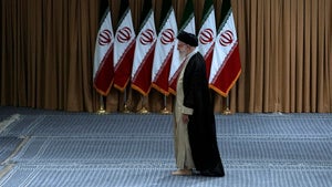 Iranian Supreme Leader Ayatollah Ali Khamenei passes in front of Iranian flags