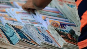 A person sorts through a stack of newspapers