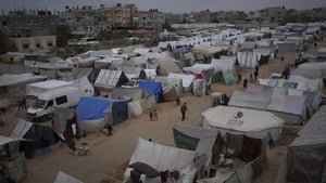 Palestinians displaced by the Israeli ground offensive on the Gaza Strip walk at the makeshift tent camp in Rafah